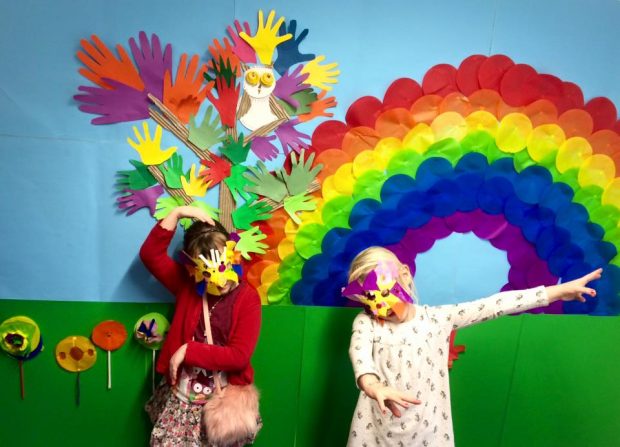 children standing in front of a rainbow artwork