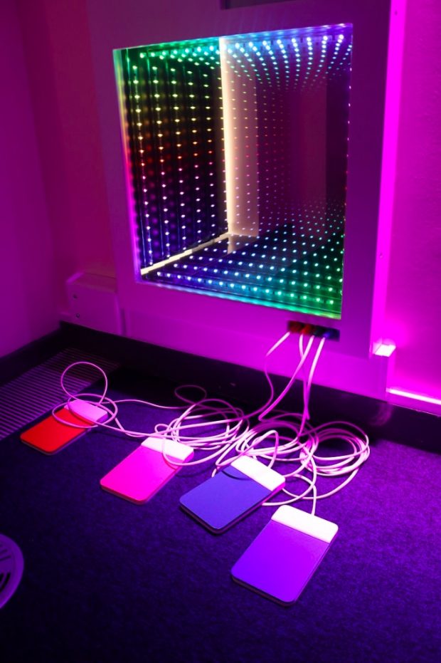 Equipment plugged into the wall in a sensory room which has a wall with lots of light diodes on