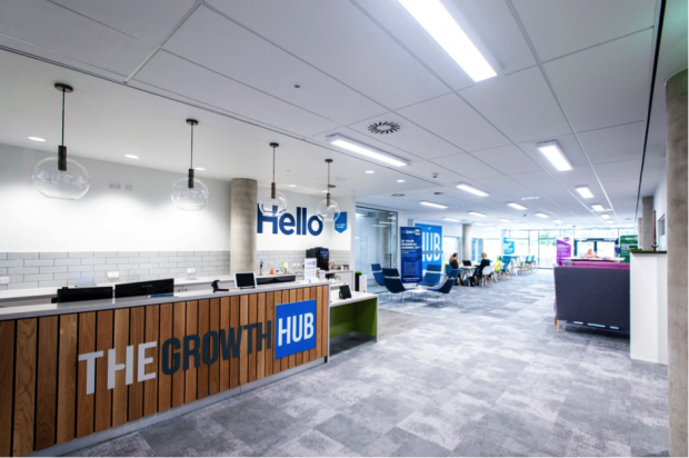 Large room with bright lights and desks, and a sign saying The Growth Hub